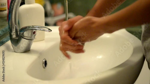 Washing of hands with liquid soap under running water.