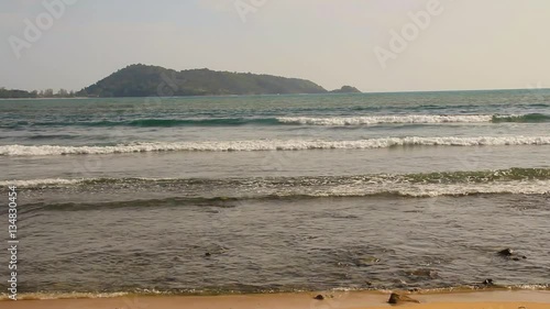 Beautiful white bubbles created on the beach by ocean waves on seashore. The ocean waves hit the rocks on the beach.