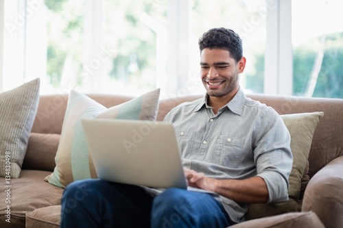 Man sitting on sofa and using laptop in living room © WavebreakMediaMicro