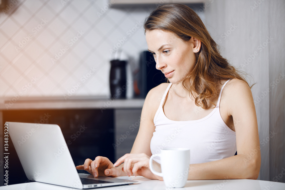Girl sits at the table at home and working on a laptop Girl sits at the table at home and working on a laptop