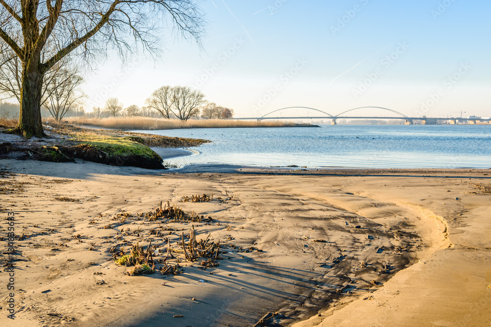 Small sandy beach along a wide Dutch river in wintertime