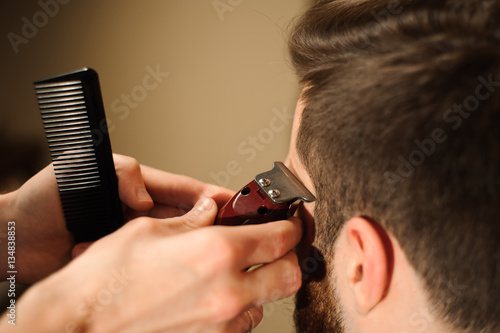 Master cuts hair and beard of men in the barbershop