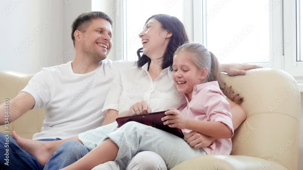 Family using digital tablet. Parents showing digital tablet to their daughter at home. Family using digital tablet. Parents showing digital tablet to their daughter at home.
