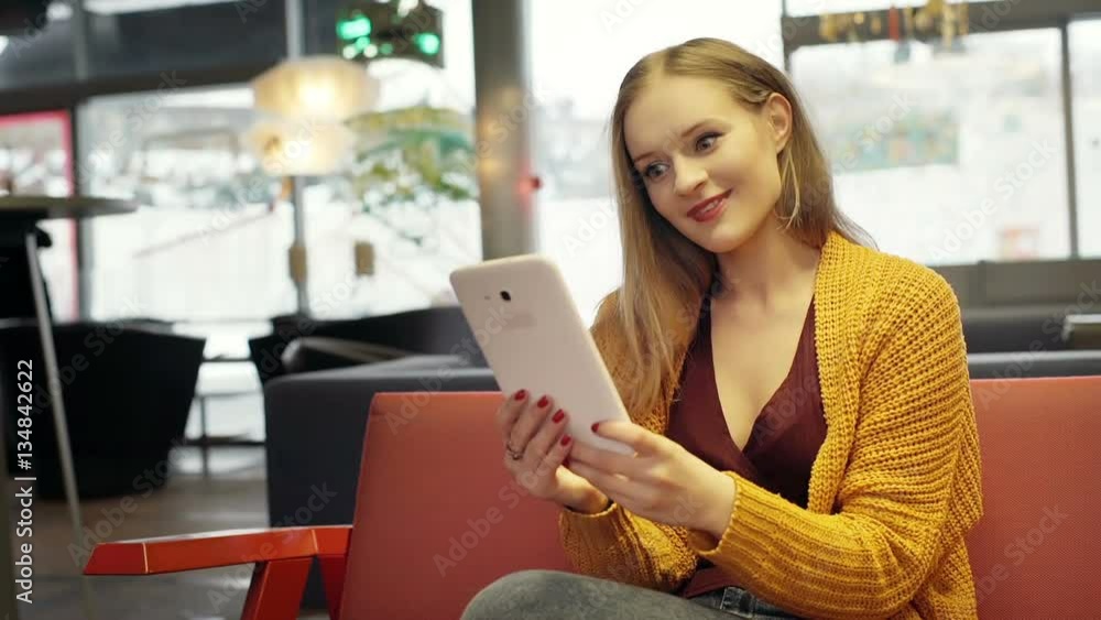 Pretty girl in yellow sweater having a videchat on tablet in the cafe
Pretty girl in yellow sweater having a videchat on tablet in the cafe