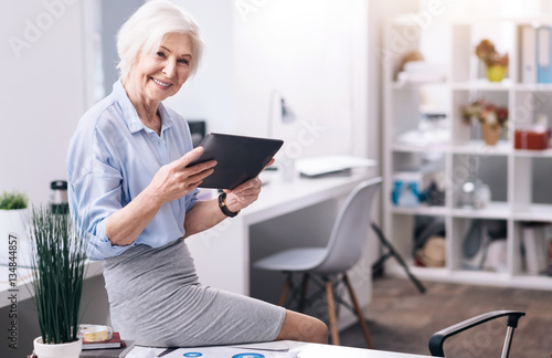 Smiling aged businesswoman using the tablet in the business center