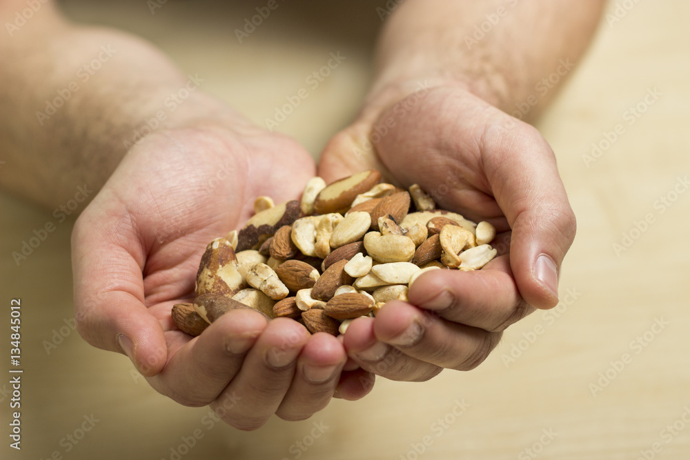 Close-up of man's hand holding a pile of nuts. Almonds, walnuts, peanuts mix in man's hands. Close-up of man's hand holding a pile of nuts. Almonds, walnuts, peanuts mix in man's hands.