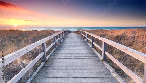 Obraz pomost prowadzący na plażę o zachodzie słońca