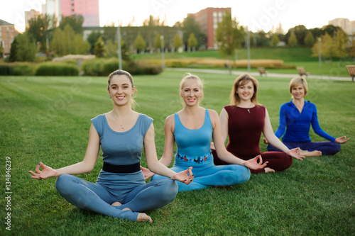 a group of adult women attending yoga outside in the park