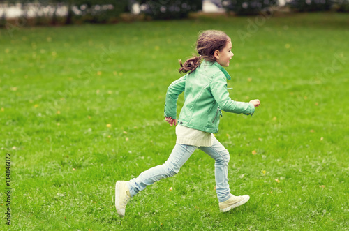 happy little girl running on green summer field