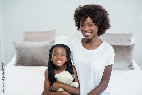 Smiling mother and daughter in bed room at home