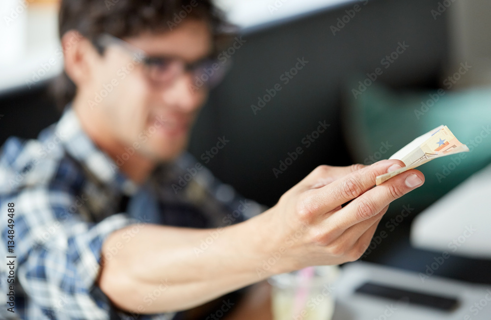 happy man with cash money paying at cafe