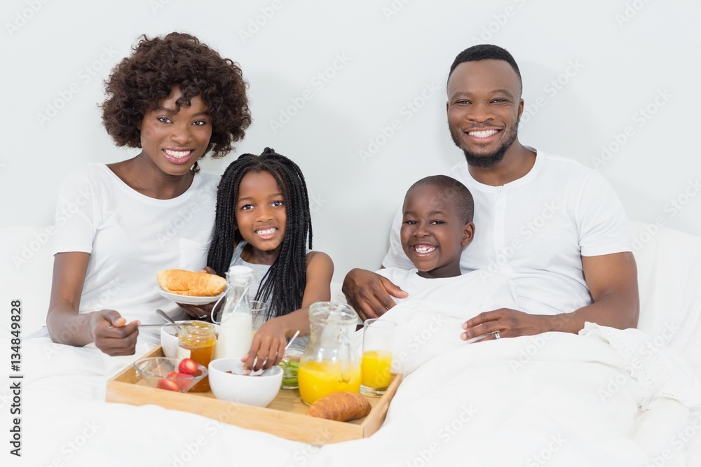 Portrait of smiling parents and kids having breakfast in bedroom Portrait of smiling parents and kids having breakfast in bedroom