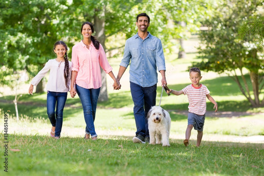 Obraz premium Happy family enjoying together with their pet dog in park