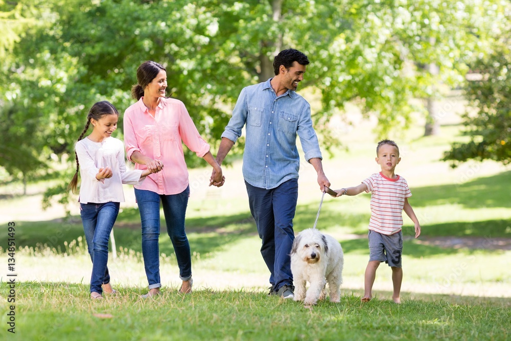 Obraz premium Happy family enjoying together with their pet dog in park