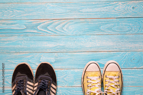 Yellow and blue sneakers stand together on blue wooden backgroun