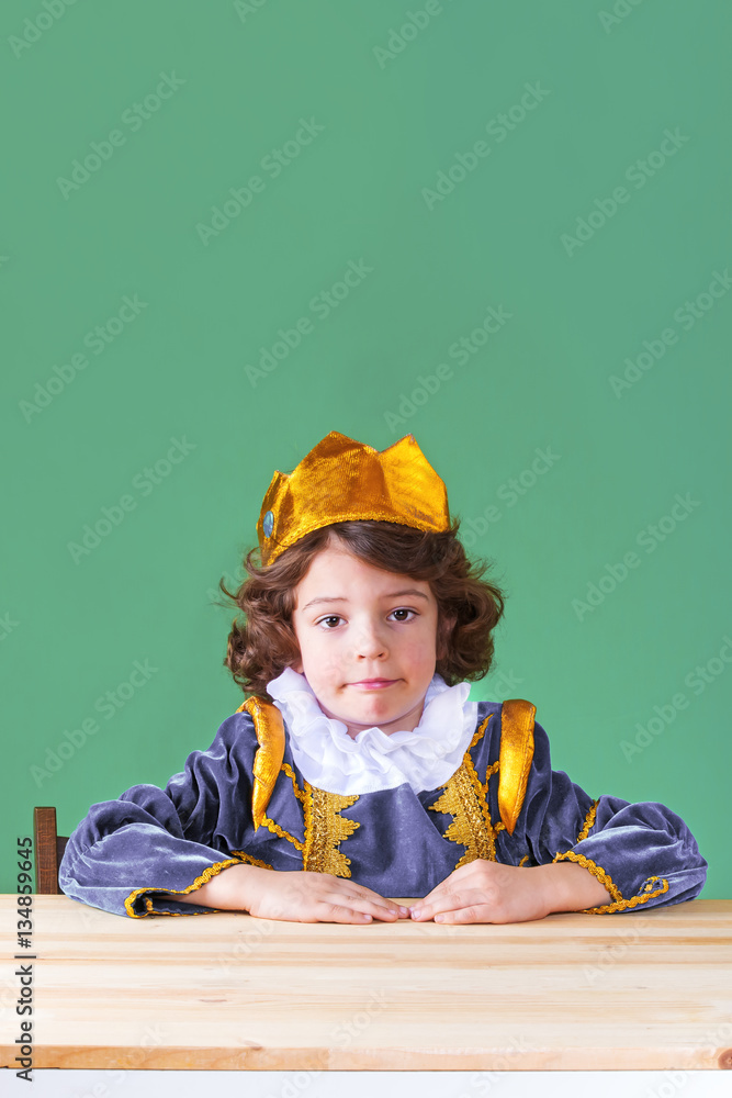 Little cute king in the crown of sad looking at the camera. Close-up. Green background. Little cute king in the crown of sad looking at the camera. Close-up. Green background.