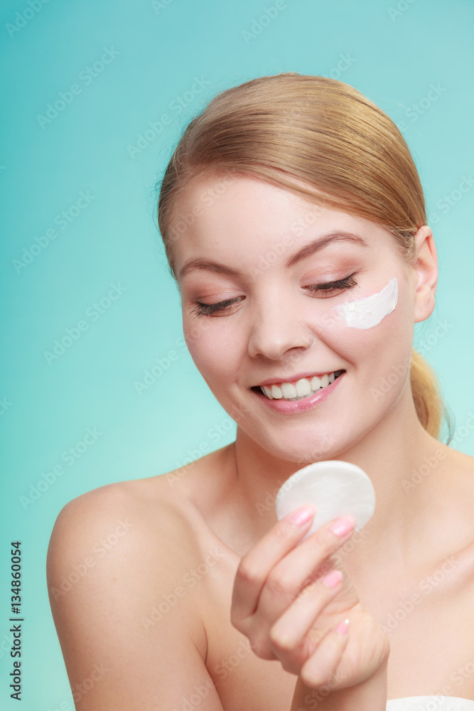 Woman removing makeup with cream and cotton pad Woman removing makeup with cream and cotton pad