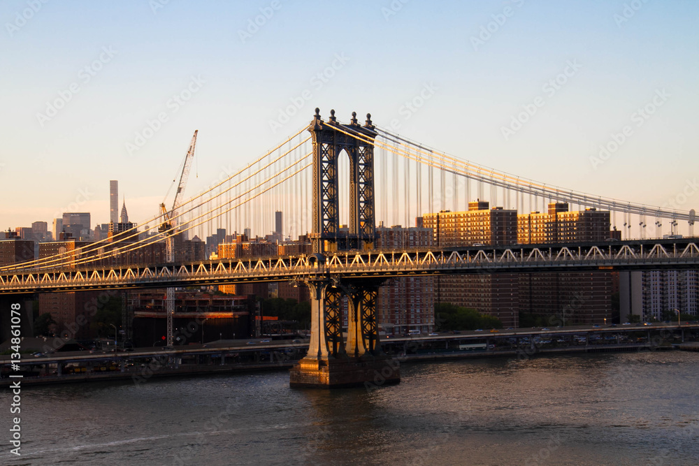 Obraz premium Manhattan bridge over the river and buildings before sunset, New York