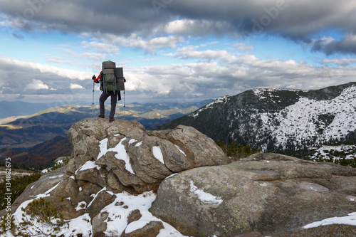 Hiker standing on a rock. Winter landscape.