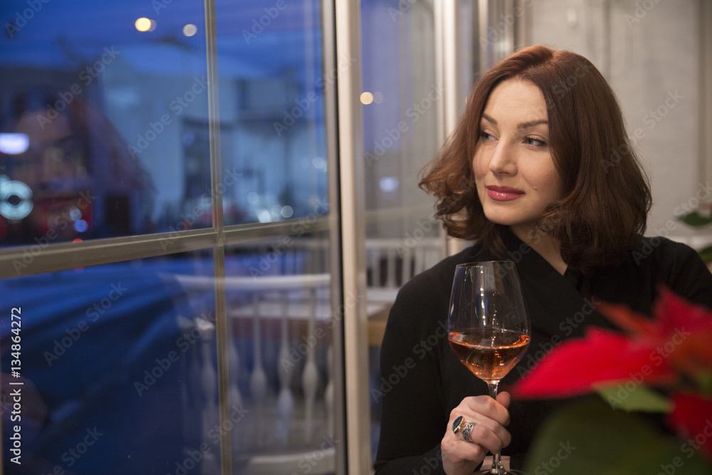 elegant young woman holding a glass of white wine and looking ou Stock ...