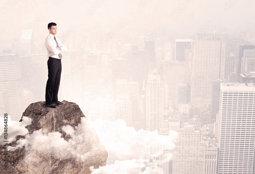 Happy businessman standing on stone top Happy businessman standing on stone top