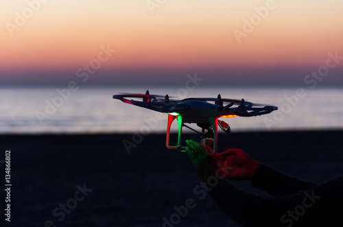 Flying drone with camera on the sky at sunset photo