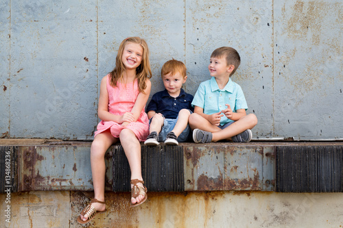 Happy children sitting on ledge together photo