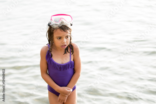 Girl in purple swim suit, shivering in water 