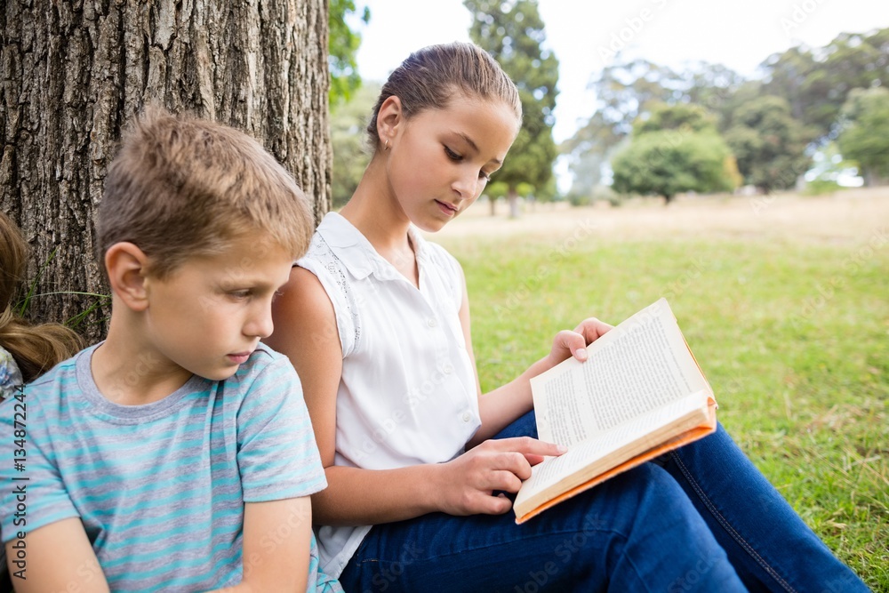 Kids reading book in park Kids reading book in park