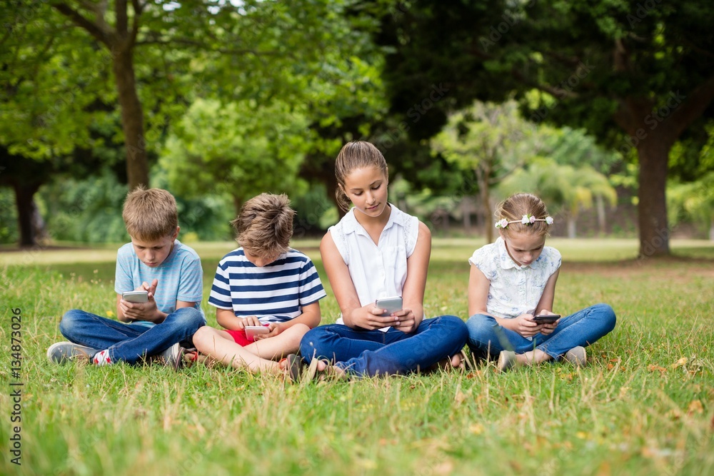 Kids using mobile phone in park Kids using mobile phone in park