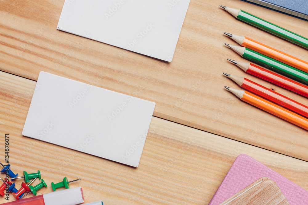 Obraz premium pencils of different colors, buttons and business cards on a wooden background