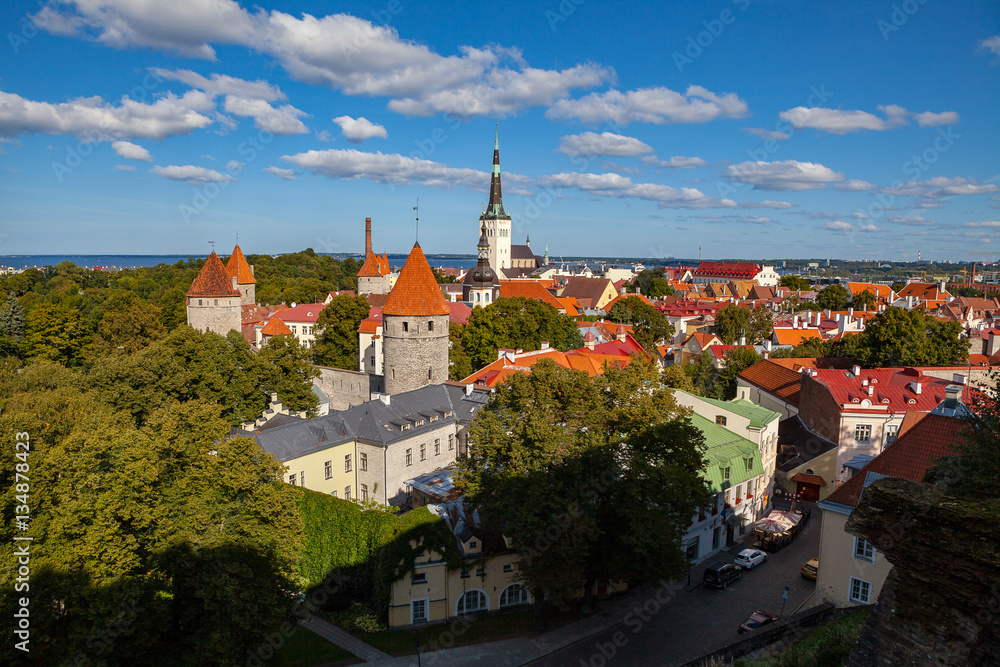 Old Town Tallinn in Estonia, Oleviste church and Baltic sea at sunny summer day. Beautiful blue sky with small clouds.