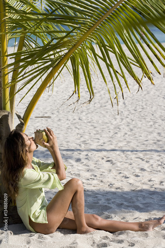 femme à la plage qui boit une noix de coco © plprod