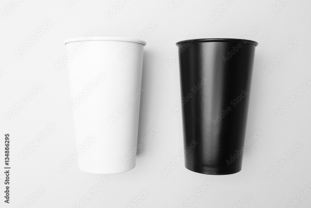 Blank white and black paper cup on the grey background Blank white and black paper cup on the grey background