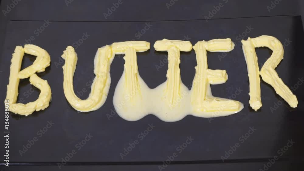 Butter being heated and melts in a skillet. Letters are made of butter melted quickly on the