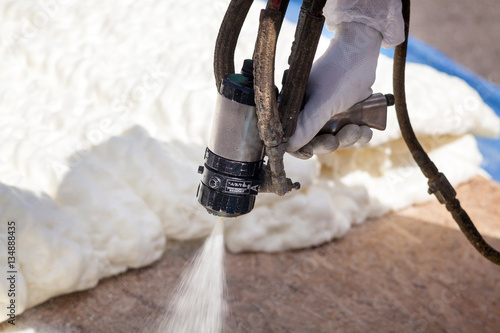 Technician spraying foam insulation using Plural Component Spray Gun photo