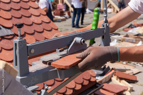 Roofer builder worker use tile cutter to create a correct size of natural red ceramic tile