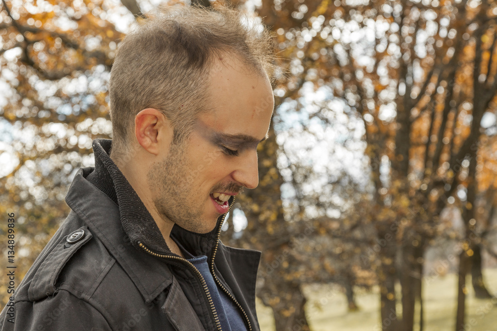 Close up portrait side ways of a young man smiling. Outdoors