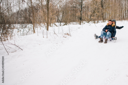 beautiful young couple riding the mountain on a sled. winter love story