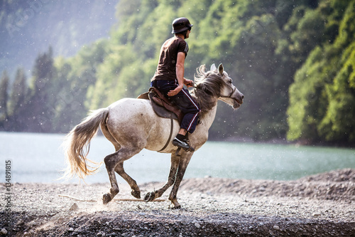 rider galloping on horseback along the river Bank