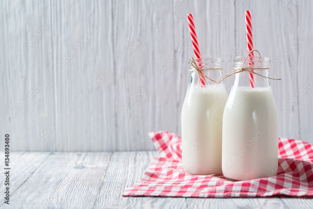 Φωτογραφία Bottles of milk with red straws and checkered towel on wooden background