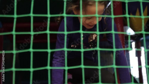 Girl crawls on the playground, over grid