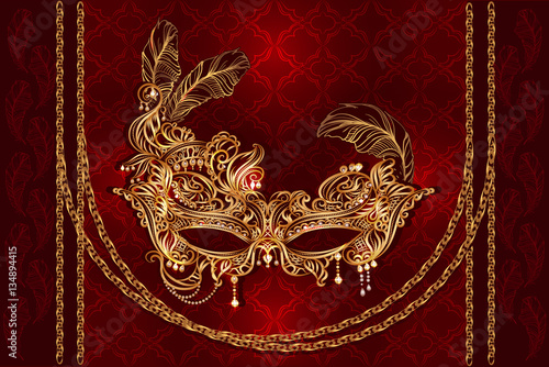 Luxury gold Venetian carnival mask with golden chains, feathers and pearls on a red velvet satiny