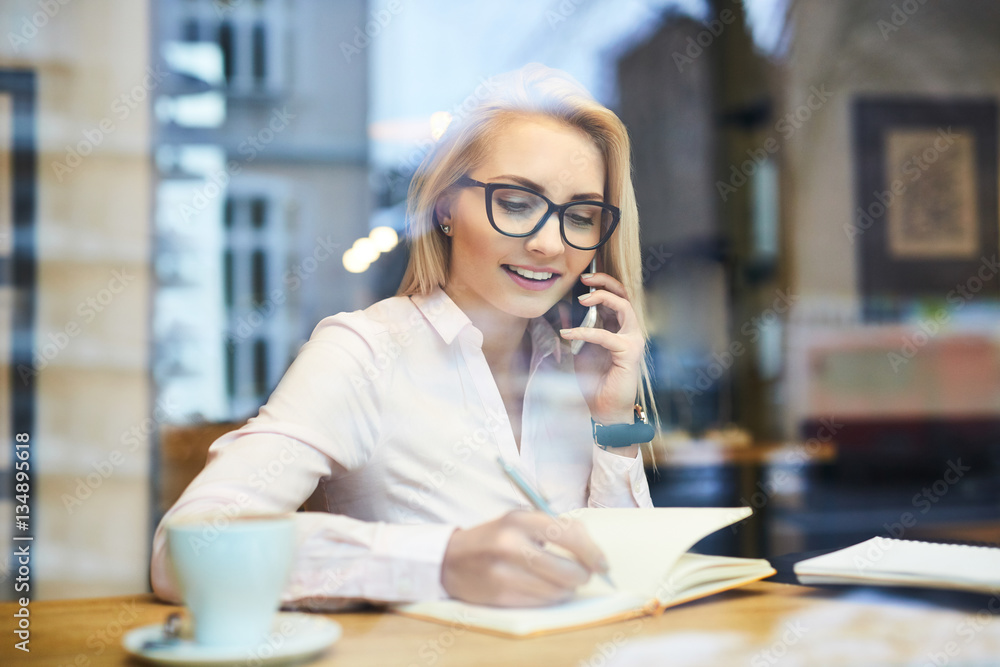 Busy businesswoman working in a cafe talking on the phone Busy businesswoman working in a cafe talking on the phone