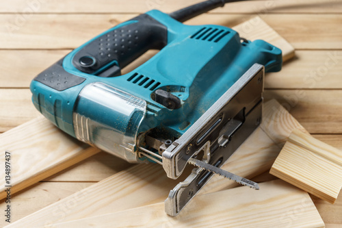Fototapeta Naklejka Na Ścianę i Meble -  Electric jigsaw closeup On wooden table, work tools concept.