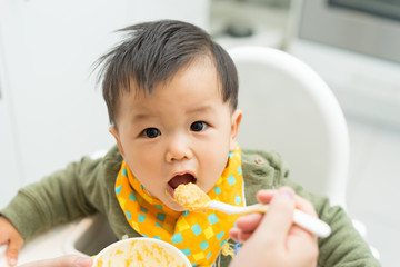 Asian baby boy eating blend food on a high chair