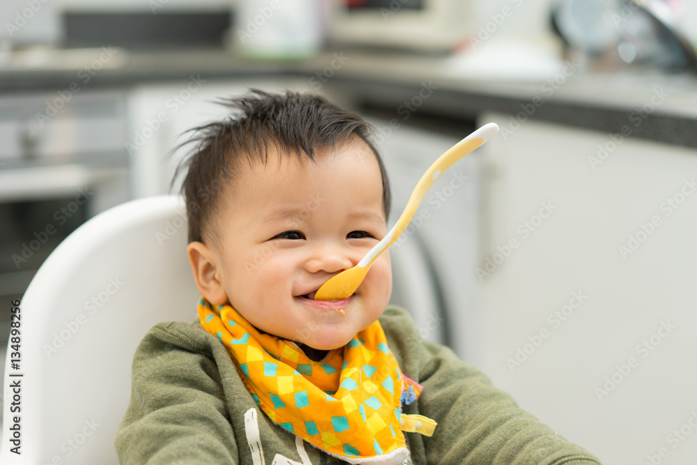 Asian baby boy eating blend food on a high chair Asian baby boy eating blend food on a high chair