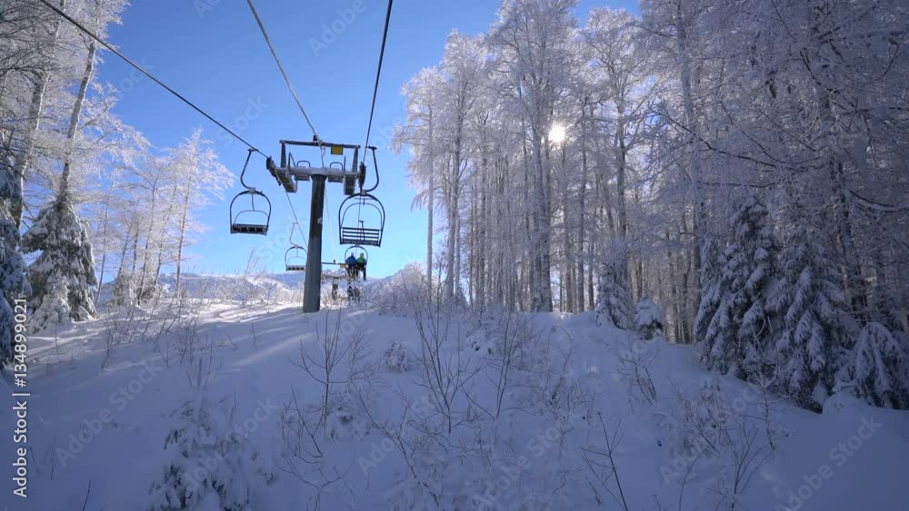 Snow forest and skiers on a ski lift pov Snow forest and skiers on a ski lift pov