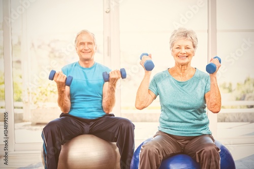 Portrait of smiling senior couple holding dumbbells