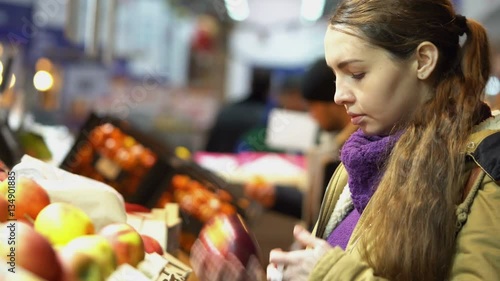 Young, beautiful pregnant woman in the supermarket selects fresh organic apples